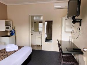 a hotel room with a bed and a desk and a television at Motel Kempsey in Kempsey