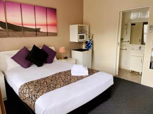 a bedroom with a large bed with purple pillows at Motel Kempsey in Kempsey +18 photos