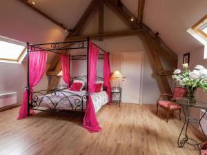 een slaapkamer met een hemelbed en roze gordijnen bij Delightful cottage surrounded by nature in Warneton