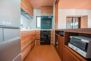 eine Küche mit Holzschränken und einer Mikrowelle in der Unterkunft むっくのおうち in Ito