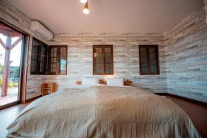 a bedroom with a large bed with a brick wall at むっくのおうち in Ito