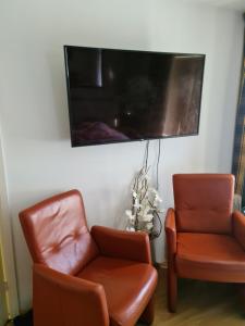 two chairs and a flat screen tv on a wall at Tamar 2 in Katwijk aan Zee