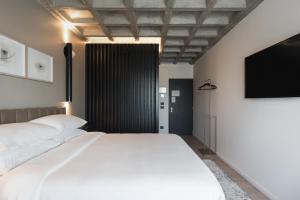 a bedroom with a white bed and a flat screen tv at Bellwort Hotel in Guadalajara