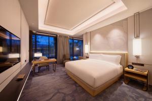 成都市にあるGran Melia Chengduのベッド、デスク、テレビが備わるホテルルームです。