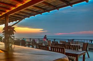 a table and chairs on the beach at sunset at Punta Zicatela Hotel - Adults Only in Puerto Escondido