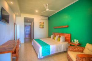 a green bedroom with a bed and a couch at Punta Zicatela Hotel in Puerto Escondido