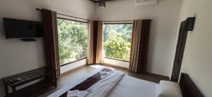 a bedroom with a bed and two large windows at Coffee and Pepper Plantation Homestay in Thekkady