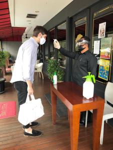 a man wearing a mask standing next to a table at White Tree Residence in Jakarta