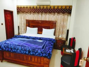 a bedroom with a bed and a chair in it at New Royal Residency PECHS in Karachi