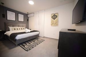 a bedroom with a bed and a flat screen tv at Geffen by the sea in Eilat