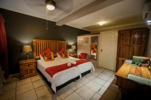 a bedroom with a large white bed with red pillows at Ivory Tusk Lodge in Tzaneen