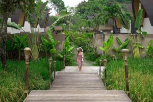 a woman walking down a wooden walkway at Lalasa Villas Canggu in Canggu