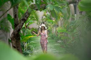 a woman walking down a path in the jungle at Lalasa Villas Canggu in Canggu