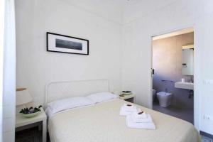 a white bedroom with a bed with two towels on it at Dune Home alloggi sul mare in Alcamo Marina