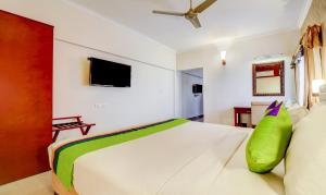 根尼亚古马里RR INN Group Of Hotels的卧室里有一张白色的大床，上面放着一个绿色的枕头