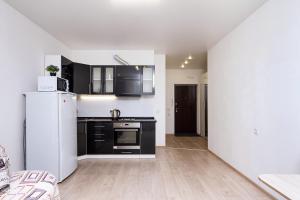 a kitchen with black cabinets and a white refrigerator at New Avrora in Novosibirsk
