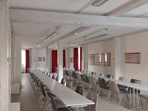 een grote kamer met tafels en stoelen en rode ramen bij Jugendherberge Rottweil in Rottweil