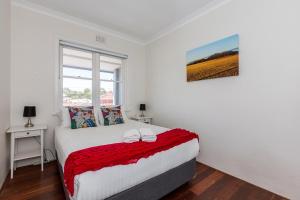 a bedroom with a bed with a red blanket at UrbanStyle Claremont Apartment in Perth