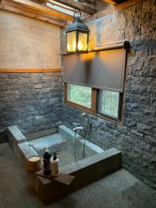 a stone bathroom with a tub with a window at 山板樵愛面子民宿 in Sanyi