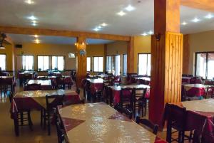 un comedor con mesas, sillas y ventanas en Hotel Gigilos Omalos, en Omalos