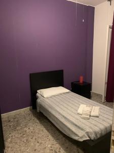 1 dormitorio con paredes moradas y 1 cama con 2 toallas en B&B Alexander, en Nápoles