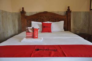 1 dormitorio con cama con almohadas rojas y manta roja en RedDoorz near Lokawisata Baturaden, en Purwokerto