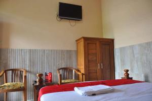 1 dormitorio con 1 cama y TV en la pared en RedDoorz near Lokawisata Baturaden, en Purwokerto