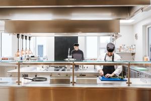 2 Köche bereiten Essen in einer Küche zu in der Unterkunft Hotel Der Stockinger in Premstätten