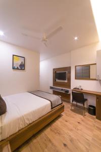 a bedroom with a bed and a desk and a tv at Sky Ridge in Vijayawāda
