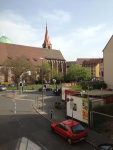 un coche rojo estacionado en un estacionamiento frente a una iglesia en City Apartment in Nürnberg Center, en Núremberg