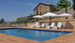 a group of white chairs and umbrellas next to a pool at Casa Serra de Dalt in Lladurs