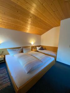 Cama grande en habitación con techo de madera en Aparts Handle und Haus Bergblick, en Pfunds