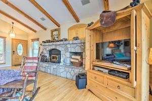 a living room with a stone fireplace and a chair at Wraparound Deck Woodland Cabin in Lake Arrowhead in Lake Arrowhead