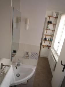 a white bathroom with a sink and a window at La petite vadrouille - coeur urbain d'Epernay in Épernay