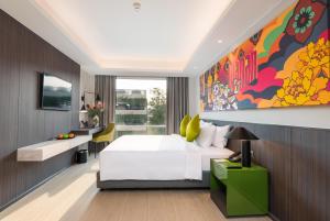 ein Schlafzimmer mit einem weißen Bett und einem großen Gemälde an der Wand in der Unterkunft Maitria Hotel Rama 9 Bangkok - A Chatrium Collection in Bangkok
