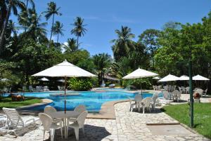 a swimming pool with white chairs and umbrellas at Hotel 7 Colinas in Olinda