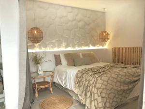 1 dormitorio con cama, mesa y luces en Casita blanca cerca de Timanfaya, en Tinguatón
