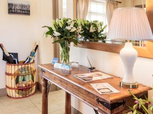 a table with a lamp and a vase of flowers on it at Meadow View in Wighton