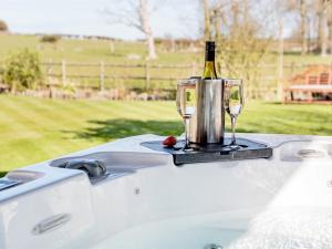 a bottle of wine and two glasses on a bath tub at Meadow View in Wighton