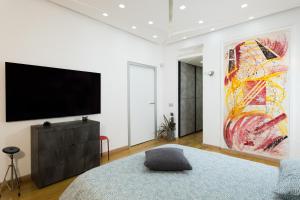 um quarto com televisão e uma grande pintura na parede em Villa Capri Apartment and Room em Nápoles
