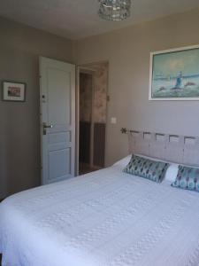 a bedroom with a large white bed with blue pillows at Chambres de Sauviolle 2 in Frontenac
