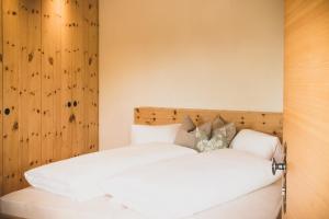 Schlafzimmer mit einem Bett mit weißer Bettwäsche und Kissen in der Unterkunft Karlshütte in Avelengo