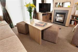 a living room with a coffee table and a fireplace at Church Farm Haven Holiday Park in Pagham