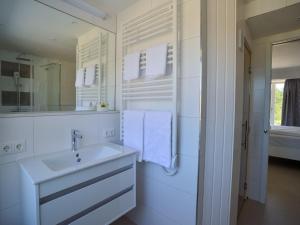 W białej łazience znajduje się umywalka i lustro. w obiekcie Dünenresidenz Prora - Proradies Oberdeck B3-4-1 w mieście Binz