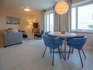 ein Wohnzimmer mit einem Tisch und blauen Stühlen in der Unterkunft Dünenresidenz Prora - Ferienwohnung mit Meerblick, 1 Schlafzimmer und Balkon NP-401 in Binz