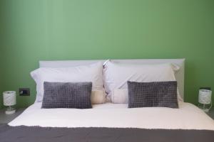 a bed with white pillows and a green wall at Casa Dante - WelcHome in Stresa +3 photos