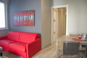 ein Wohnzimmer mit einem roten Sofa und einem Tisch in der Unterkunft Casa Dante - WelcHome in Stresa