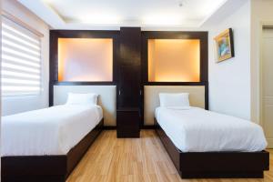 two beds in a room with white sheets at Northpointe Residences in Manila