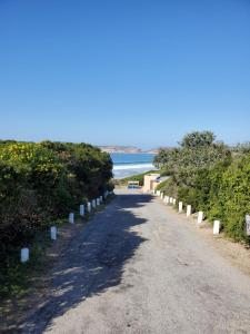 a road leading to the beach with the ocean in the background at Long Story Guest House in Plettenberg Bay