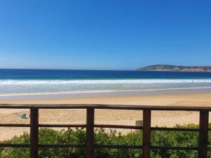 a view of a beach with a fence and the ocean at Long Story Guest House in Plettenberg Bay